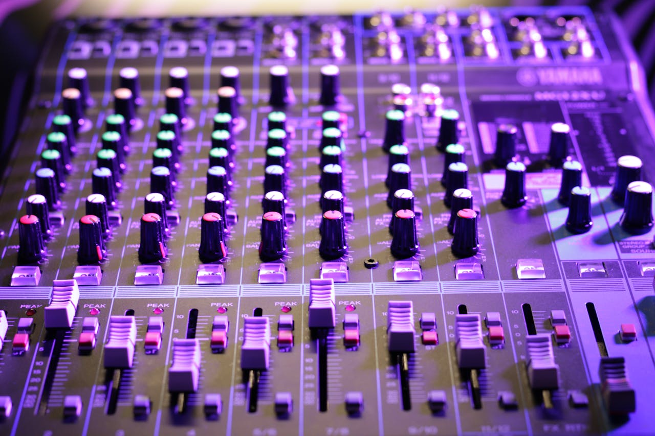 Close-up of a professional audio mixer console with glowing knobs and sliders, ideal for music production.